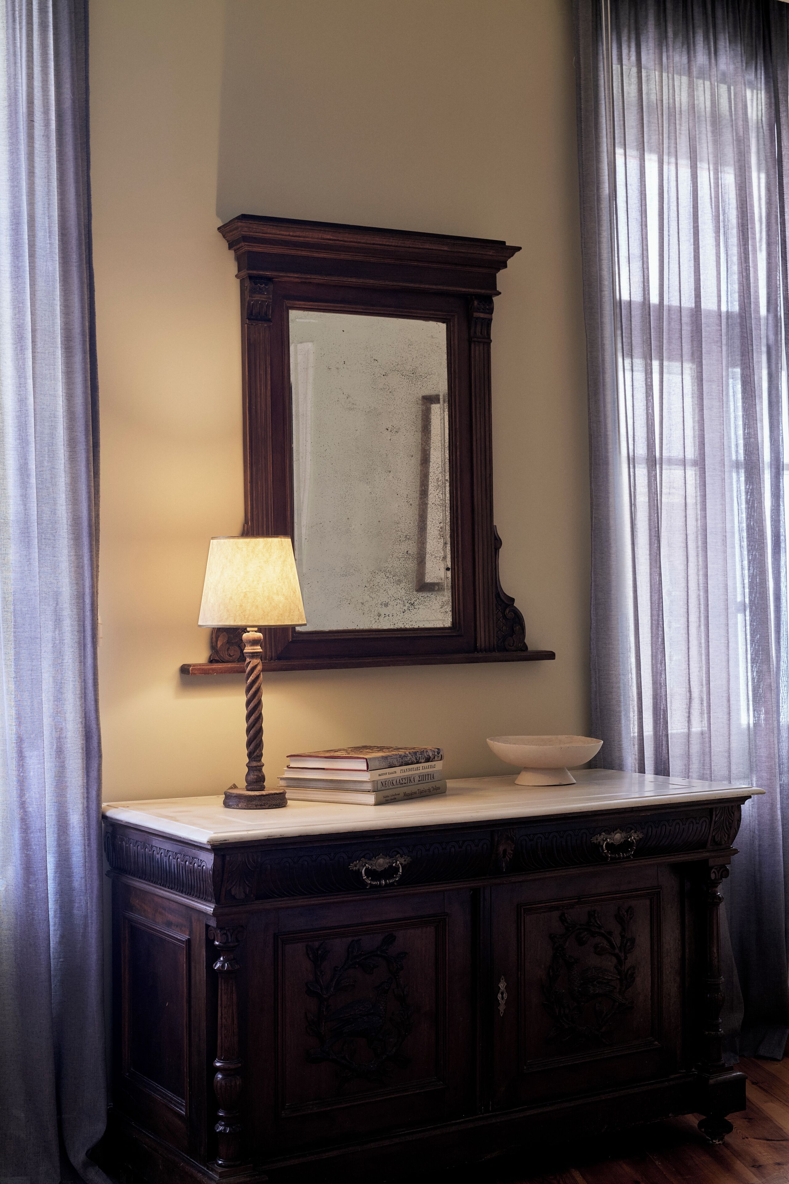 A dark wooden dresser with a mirror, a lamp, and a bowl on top.
