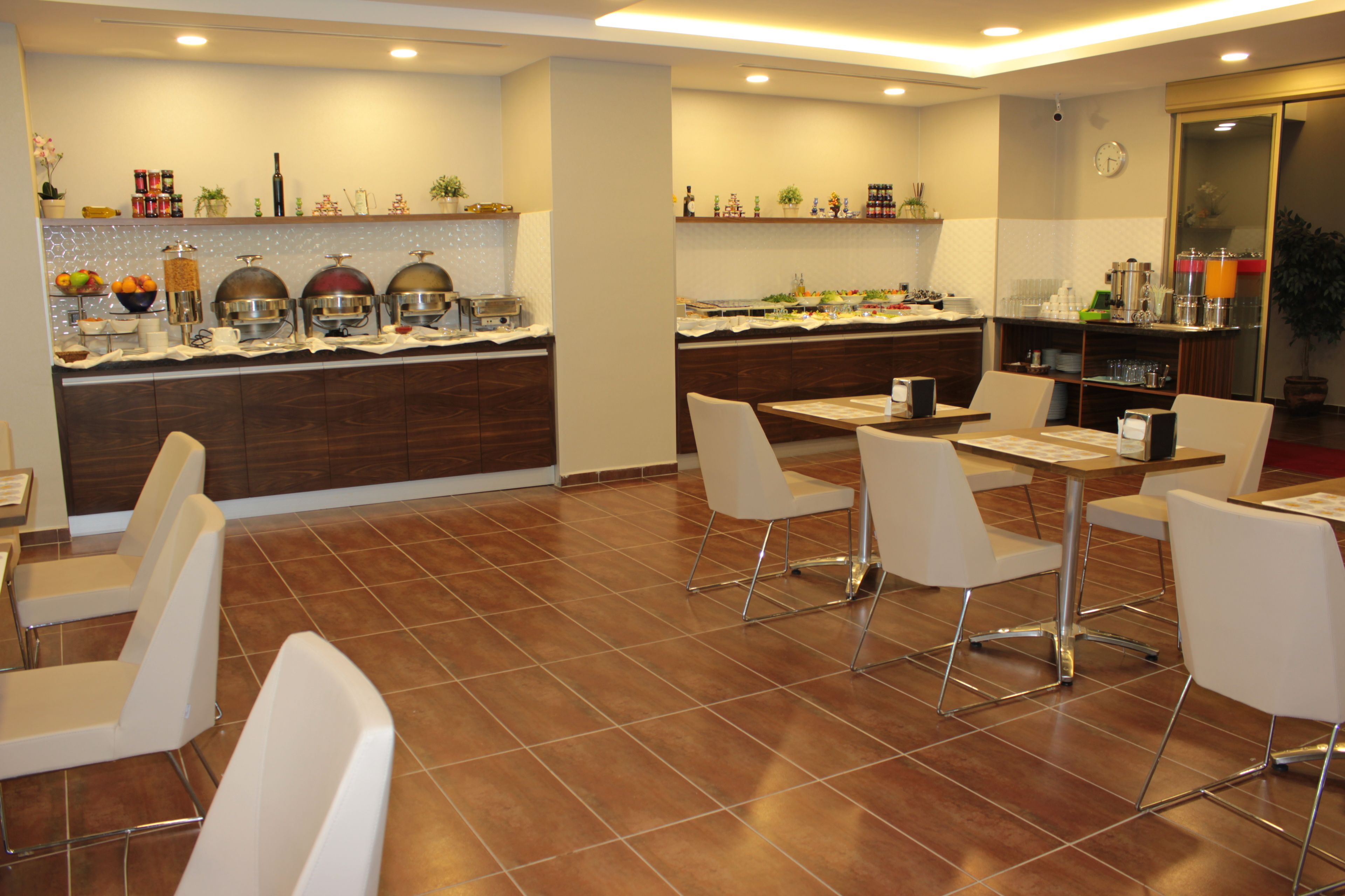 Un restaurante moderno con mesas de buffet, sillas blancas y piso de baldosas.