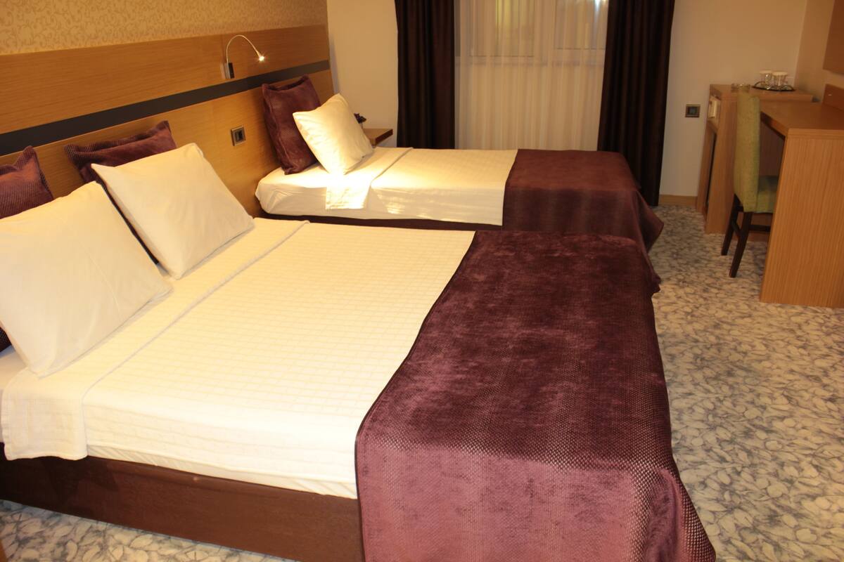 Een hotelkamer met twee bedden, een bureau en een stoel.