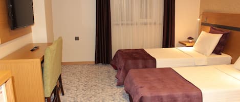 A hotel room with two beds, a desk with a chair, a television, and a window with curtains.