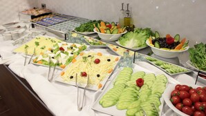 Buffet com diversos alimentos, incluindo saladas, legumes e frutas.