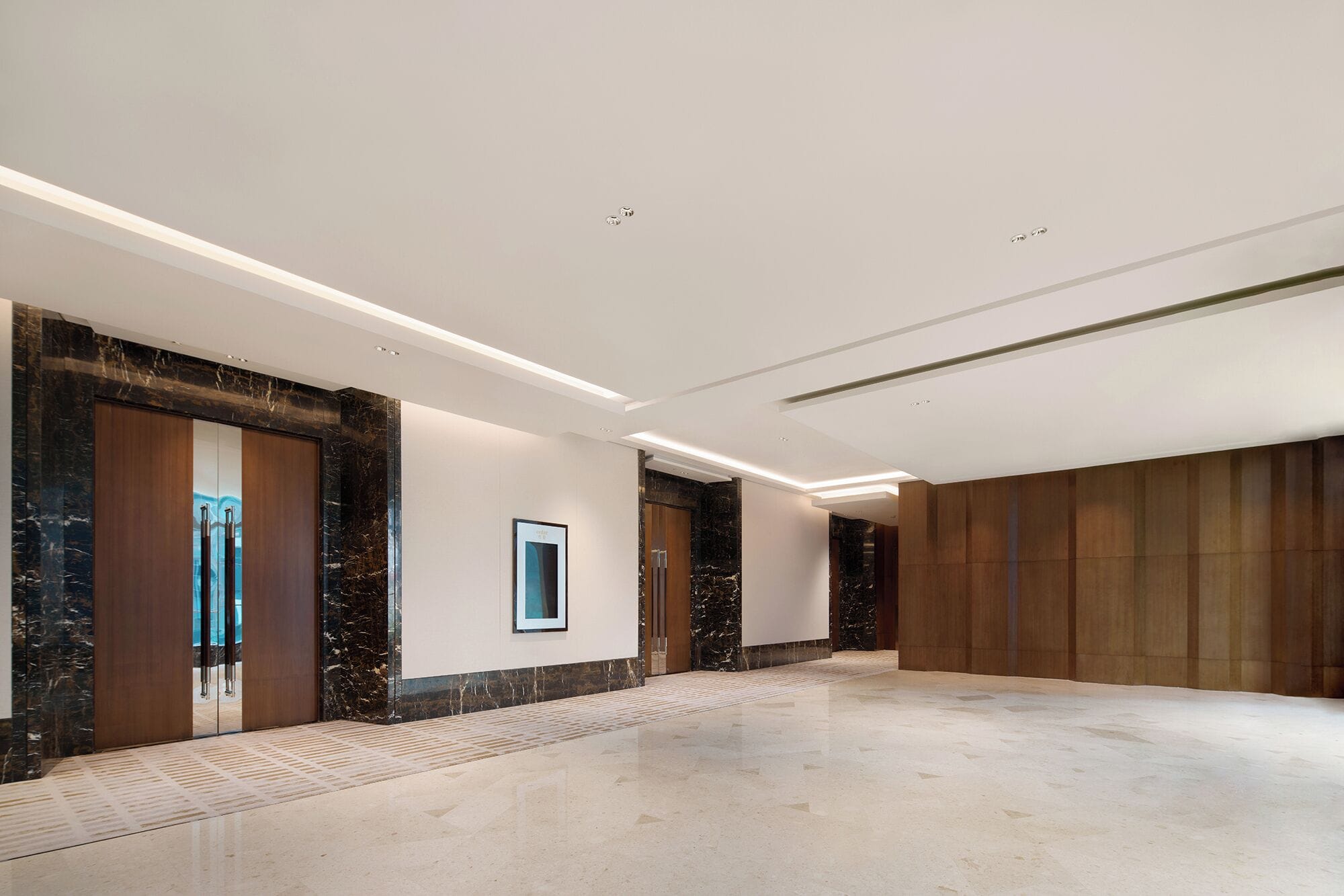 A spacious hallway with marble flooring, wooden paneling on the walls, and recessed lighting.