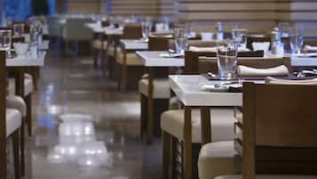 Un restaurante con mesas dispuestas para comer, iluminación decorativa en el techo y un interior limpio y moderno.