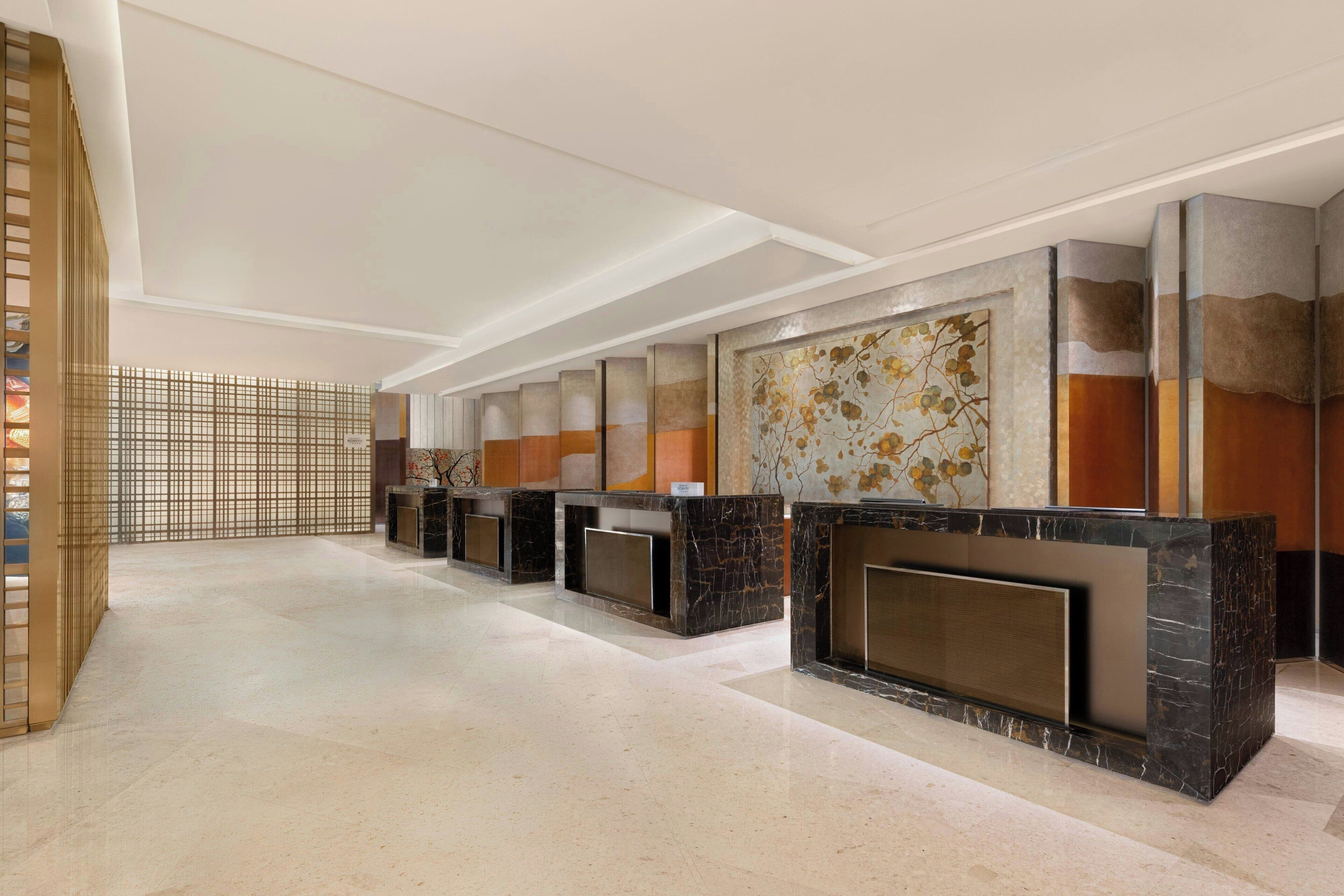 A hotel lobby with a reception desk, a decorative wall, and a traditional partition.
