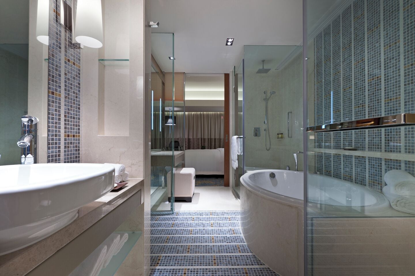Ein modernes Badezimmer mit einer großen Badewanne, einer separaten Duschkabine und einem Glas-Waschtisch.