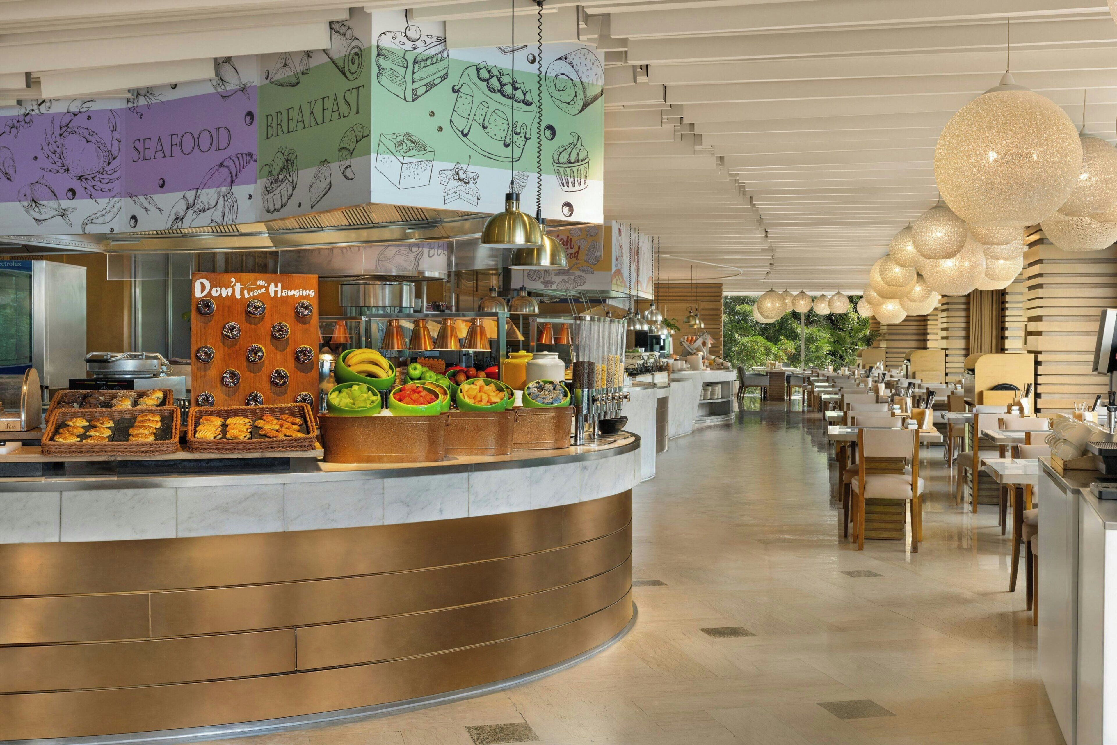 Een modern restaurant met een gebogen toonbank, diverse gerechten en hangende decoraties.