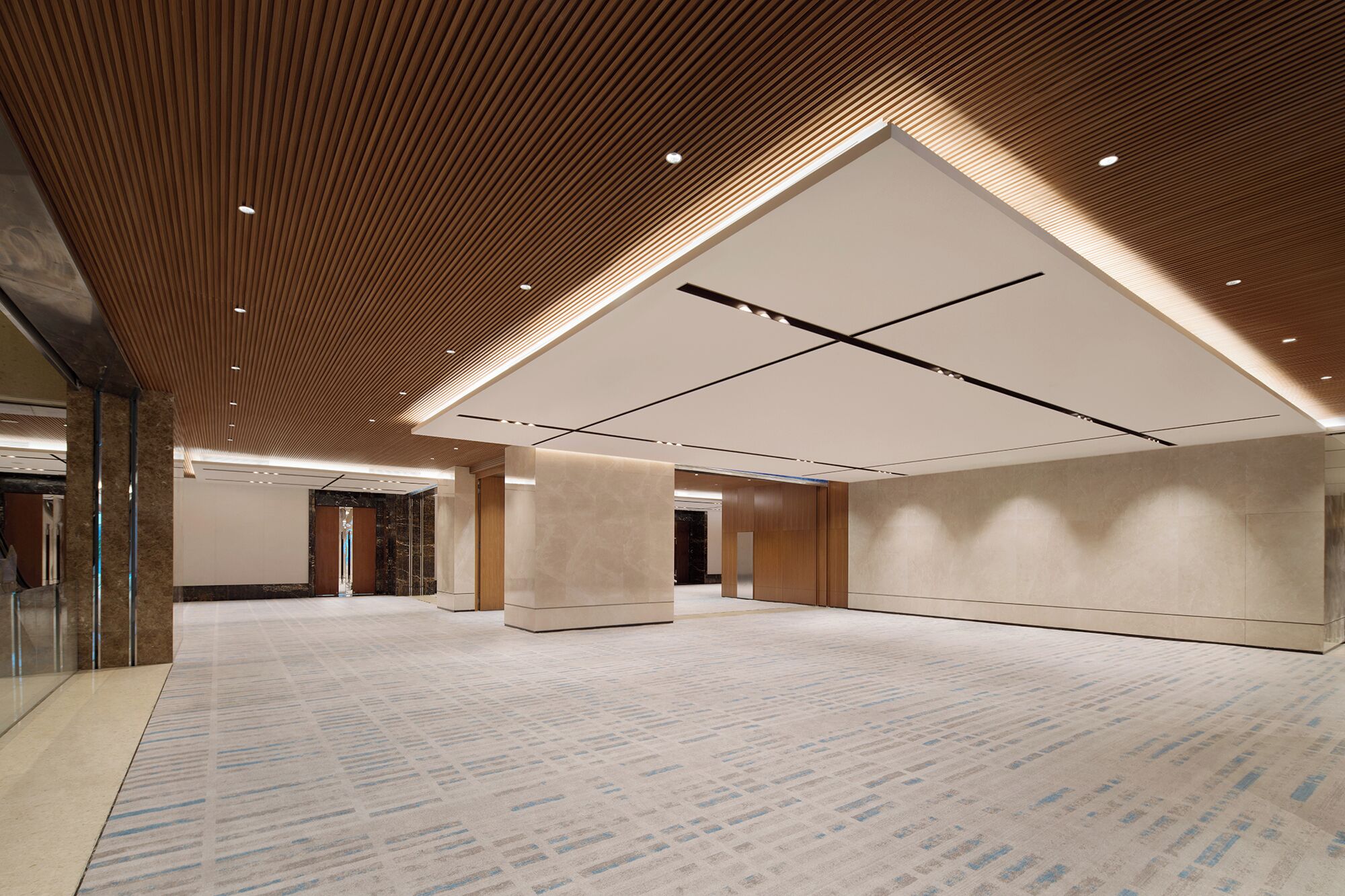 A spacious lobby with a high ceiling, recessed lighting, and a patterned carpet.