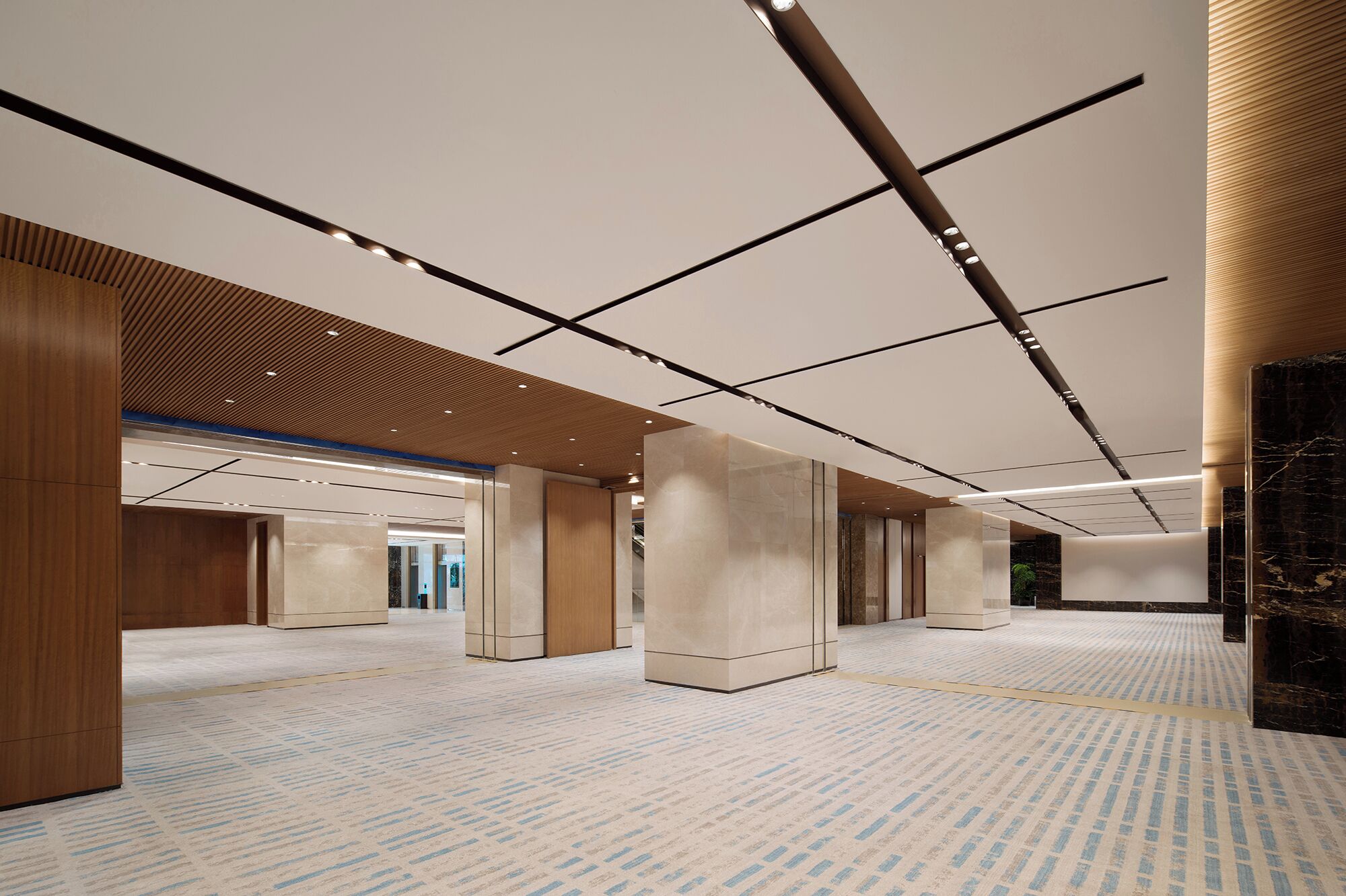 Een ruime hotellobby met een hoge plafond, ingebouwde verlichting en een kamerbreed tapijt.