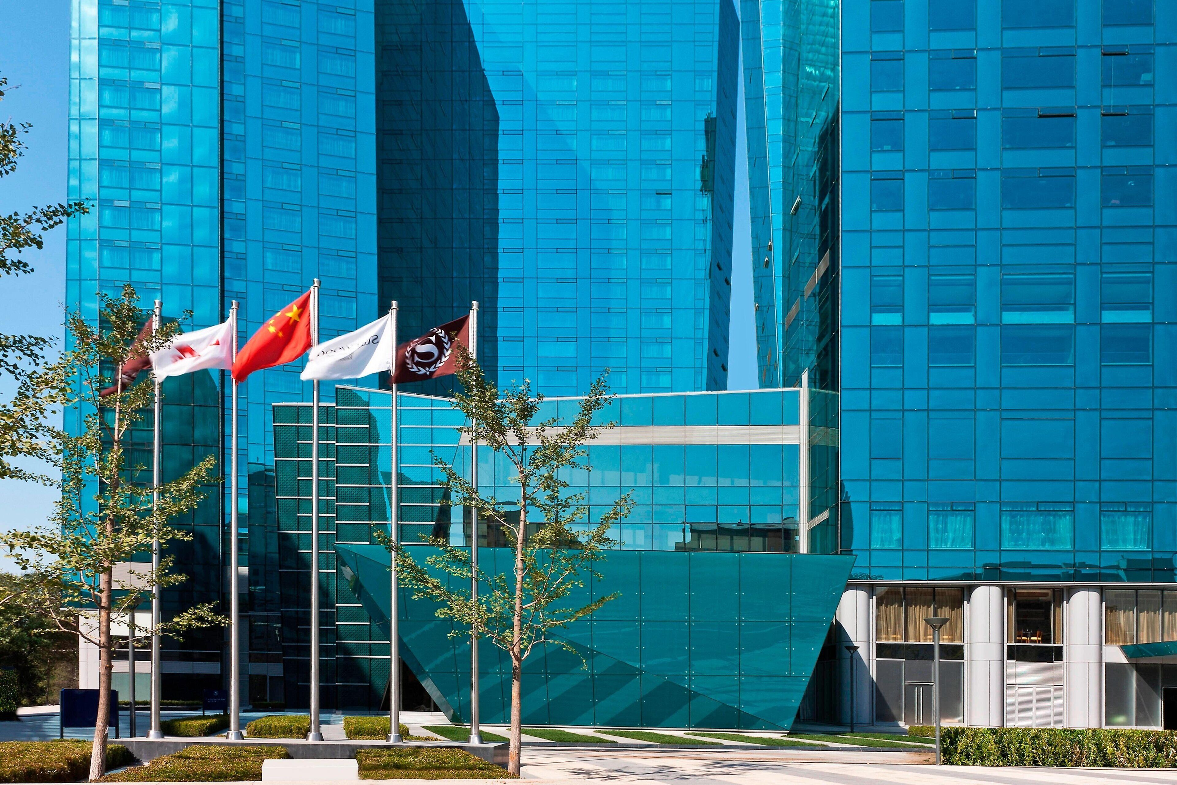 A modern building with a glass facade and multiple flags.