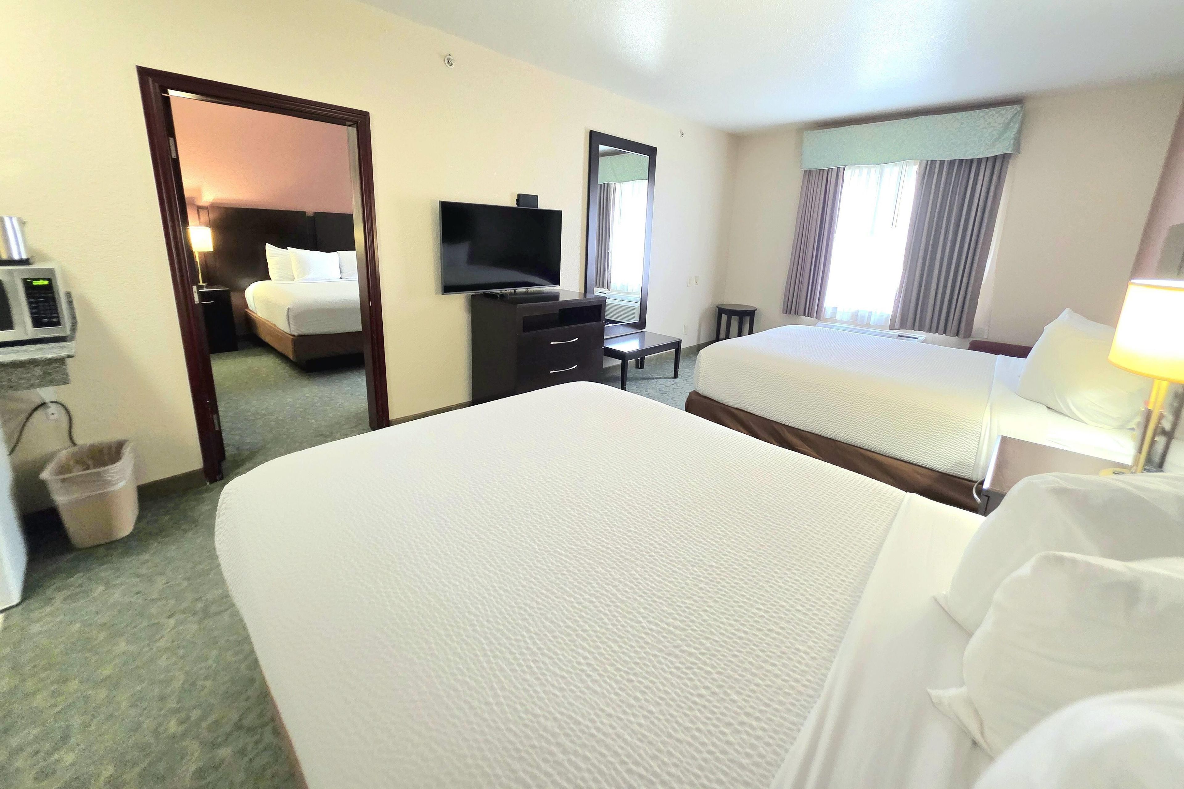 Habitación de hotel con dos camas, un televisor, un escritorio y un espejo.