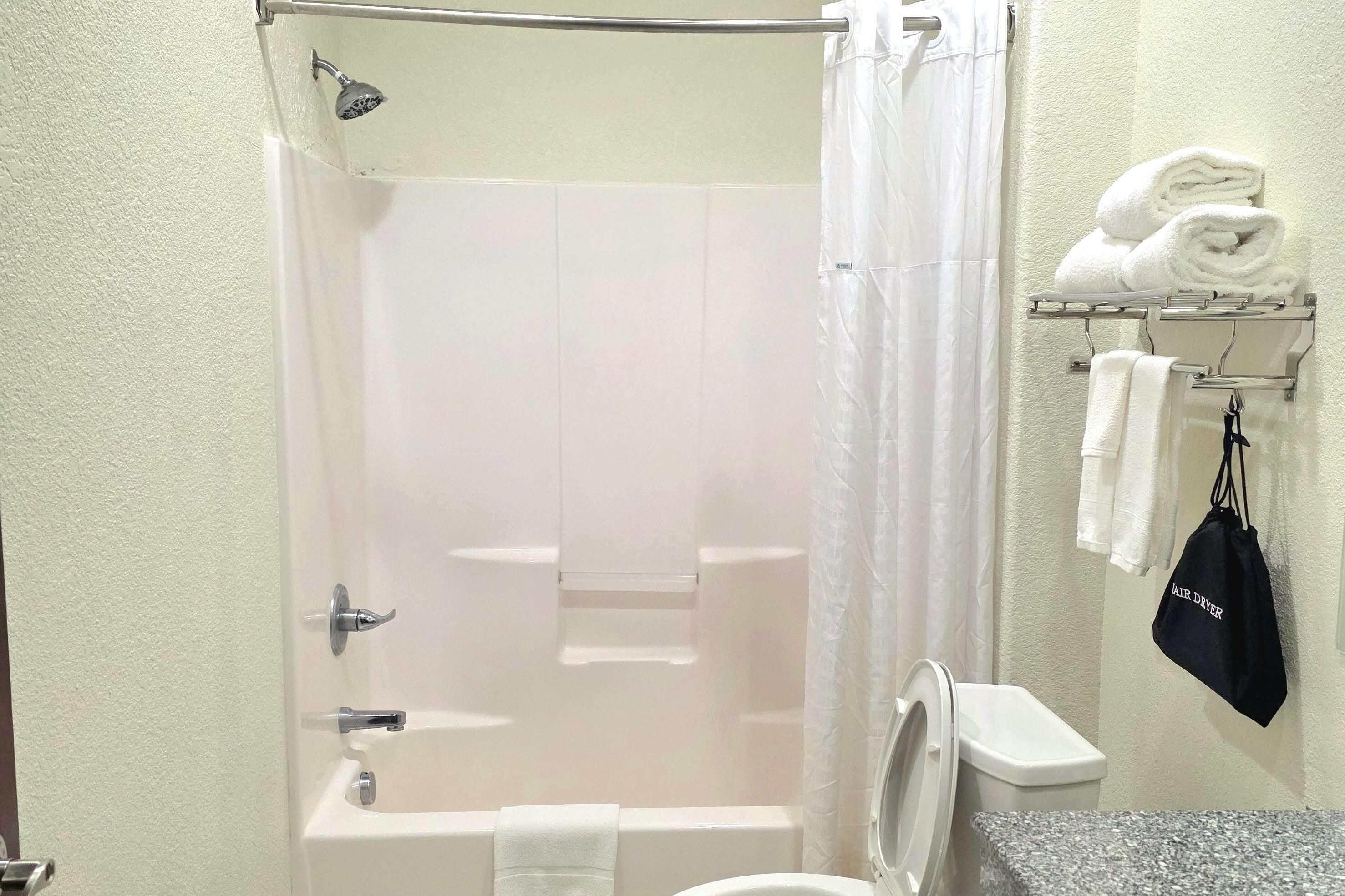 A bathroom with a shower, toilet, and a towel rack with towels.