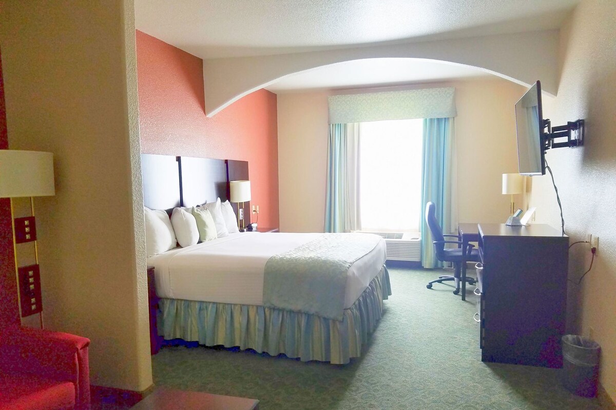 A hotel room with a bed, desk, chair, and a television.