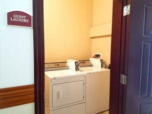 A laundry room with a sign reading "Guest Laundry" and a washing machine. - Ramada by Wyndham South Waco (Hewitt)