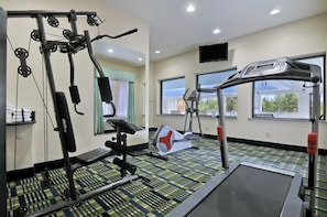 Ein Fitnessraum mit Trainingsgeräten, Laufband und Fenstern mit Aussicht.