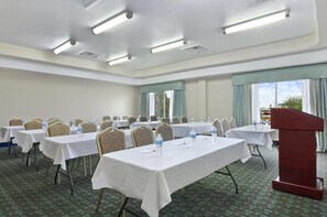 A conference room with tables, chairs, and a podium. - Ramada by Wyndham South Waco (Hewitt)