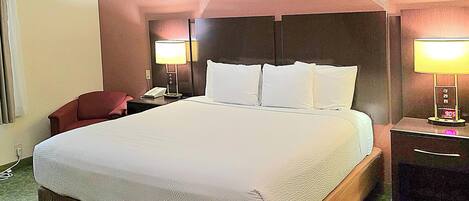 A hotel room with a large bed, two bedside lamps, a nightstand, and a chair.