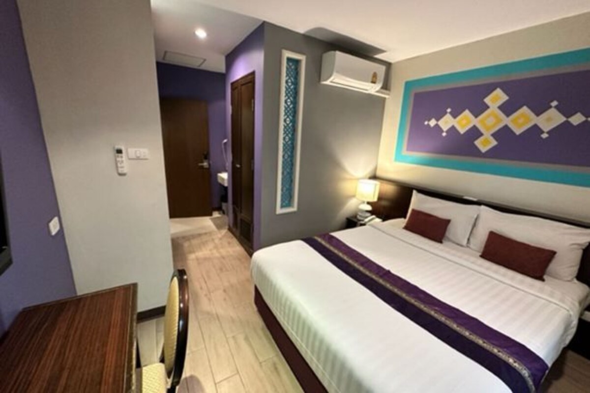 A hotel room with a bed, a desk, and a chair.