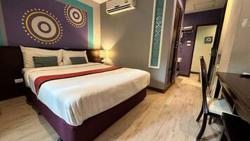 Een hotelkamer met een bed, een bureau en een stoel. Er is een airconditioningapparaat aan de muur.