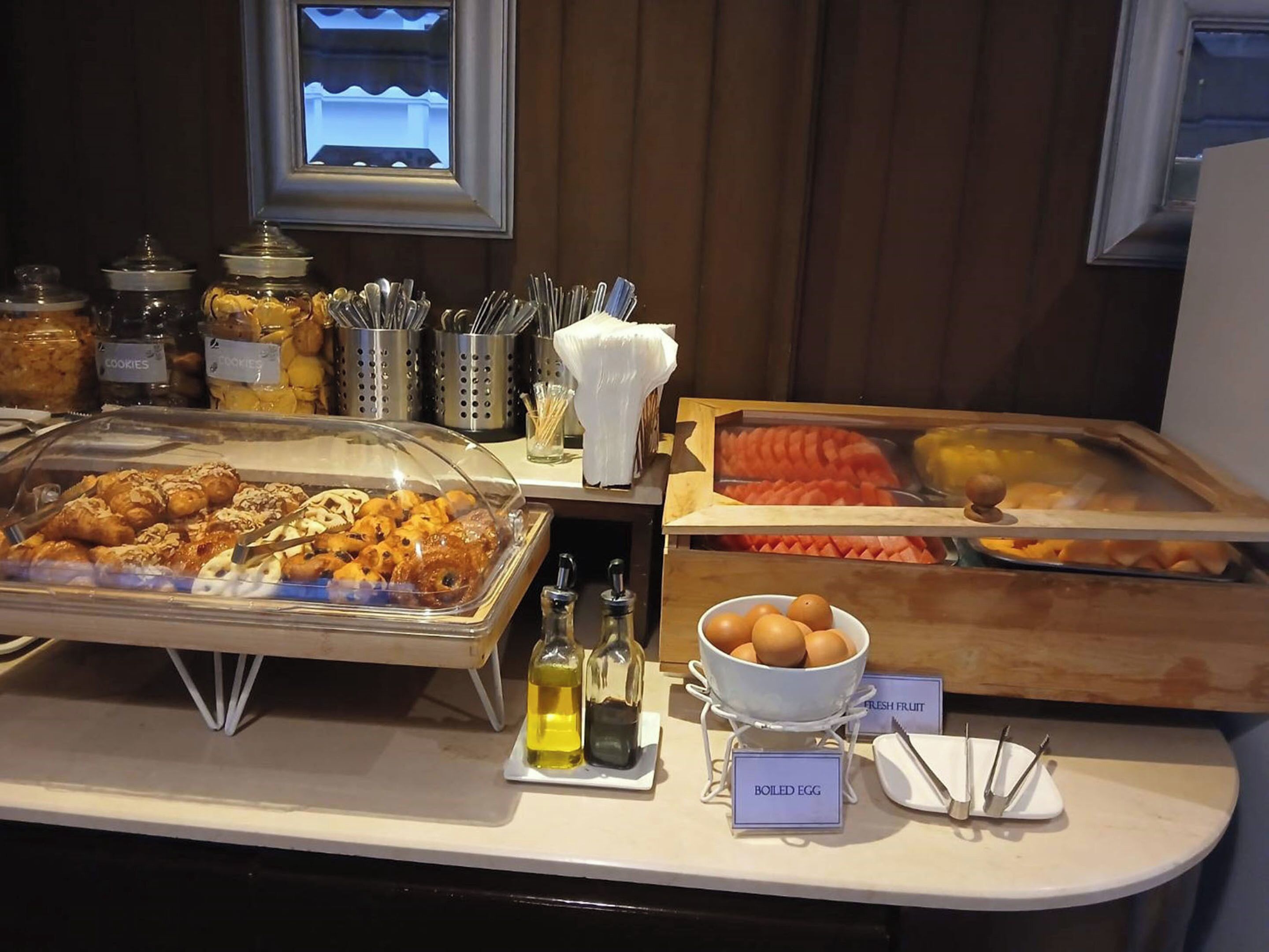 A buffet with various food items including cookies, boiled eggs, fresh fruit, and pastries.