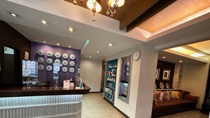 Un área de recepción con mostrador, pared decorada con círculos, un reloj y zona de estar con cojines.