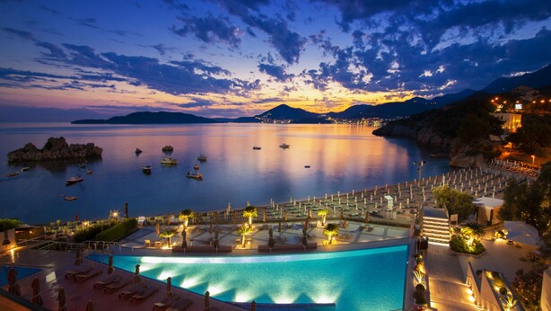 Un resort con piscina, sillones de descanso y sombrillas.