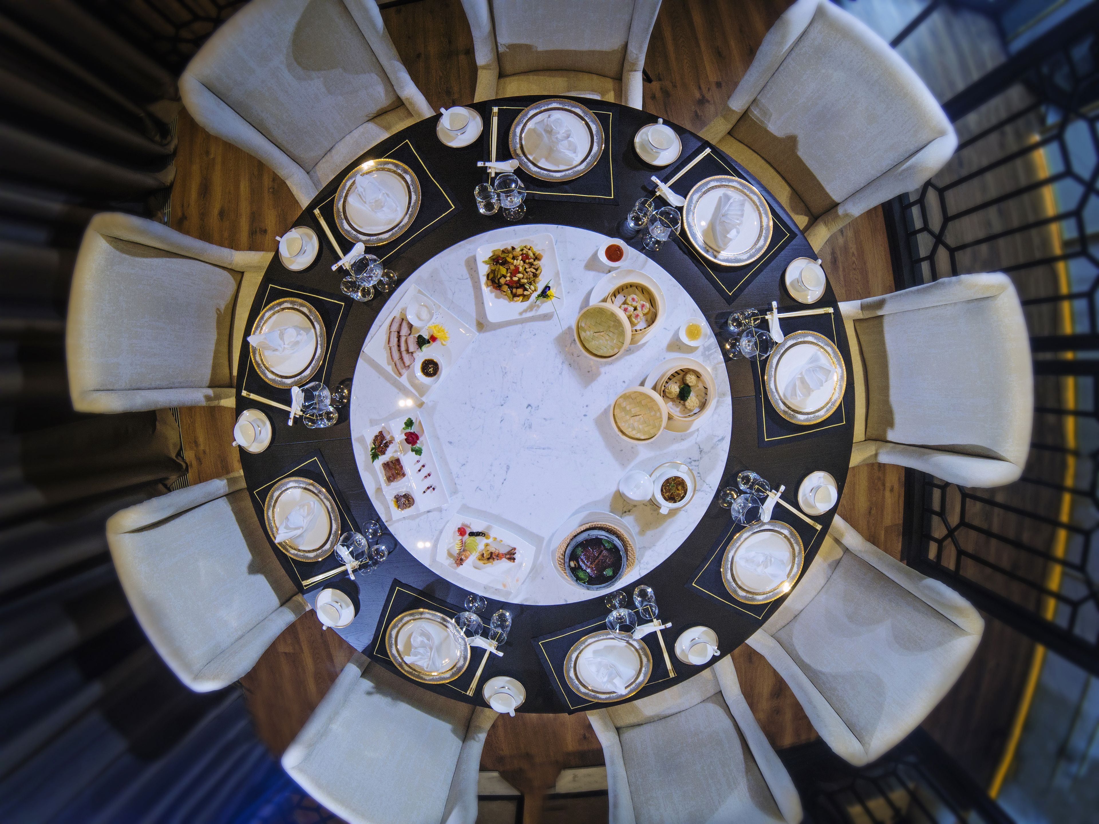Una mesa redonda de comedor con varias sillas, rodeada de diferentes platos y cubiertos.
