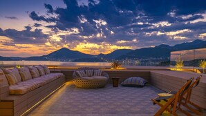 Una terraza en la azotea con un sofá, un espacio de estar circular y una silla de madera.
