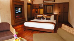 A hotel room with a large bed, a television, wooden furniture, and a fruit basket. - Montien House Chaweng Beach Resort (Koh Samui)