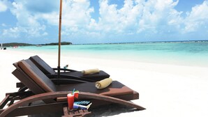 A beachside lounge with a white umbrella, lounge chairs, and a drink with a straw. - Montien House Chaweng Beach Resort (Koh Samui)