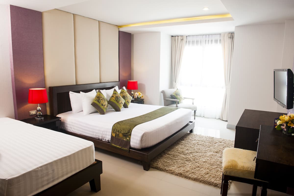 Quarto de hotel com duas camas, uma escrivaninha, uma cadeira e uma televisão.