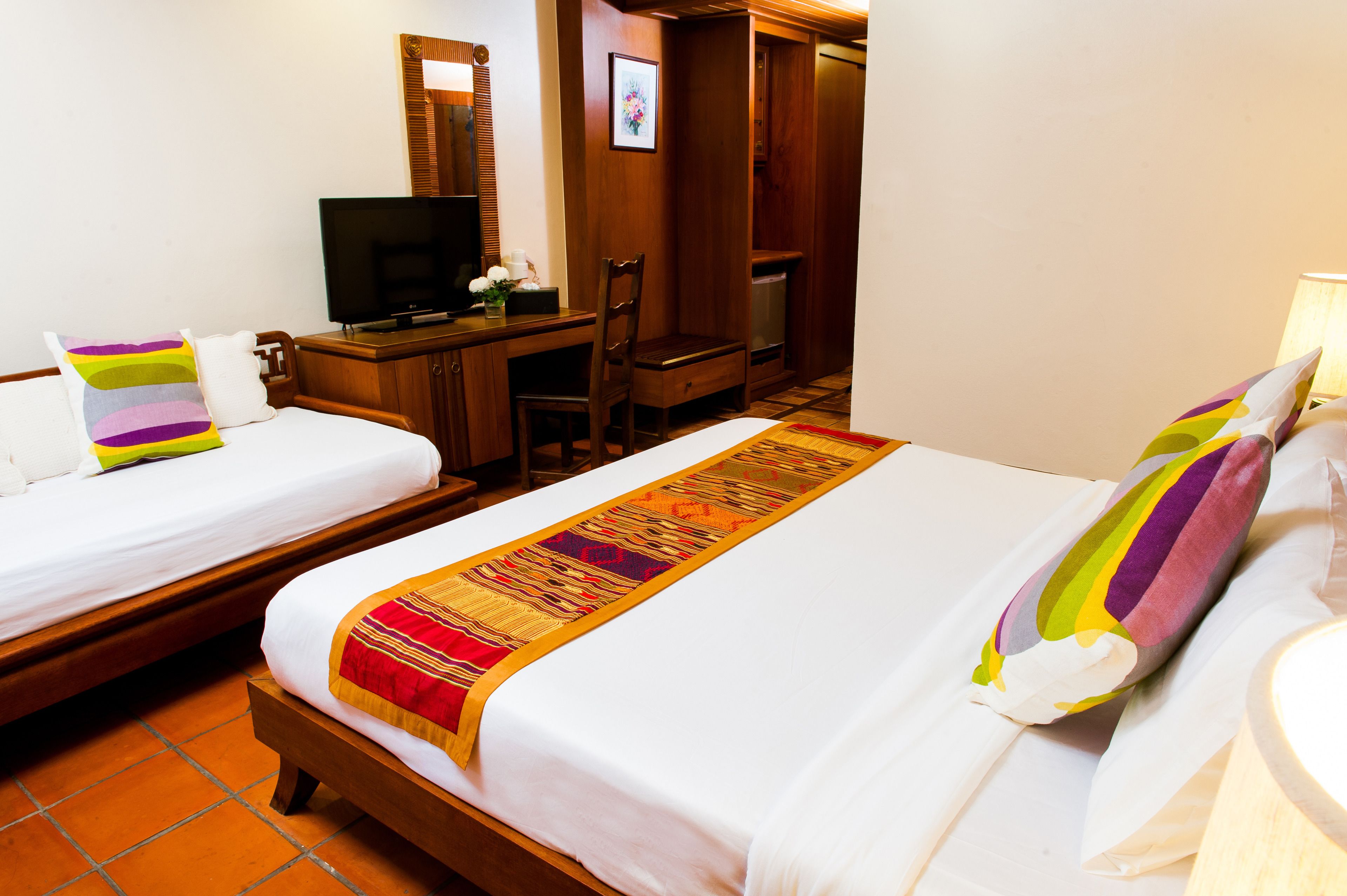 A hotel room with two beds, a television, a desk, and a chair.