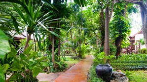 A pathway flanked by lush greenery and a large black pot. - Montien House Chaweng Beach Resort (Koh Samui)