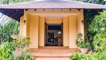 A building entrance with a tiled roof, a beige facade, and steps leading up to a door.