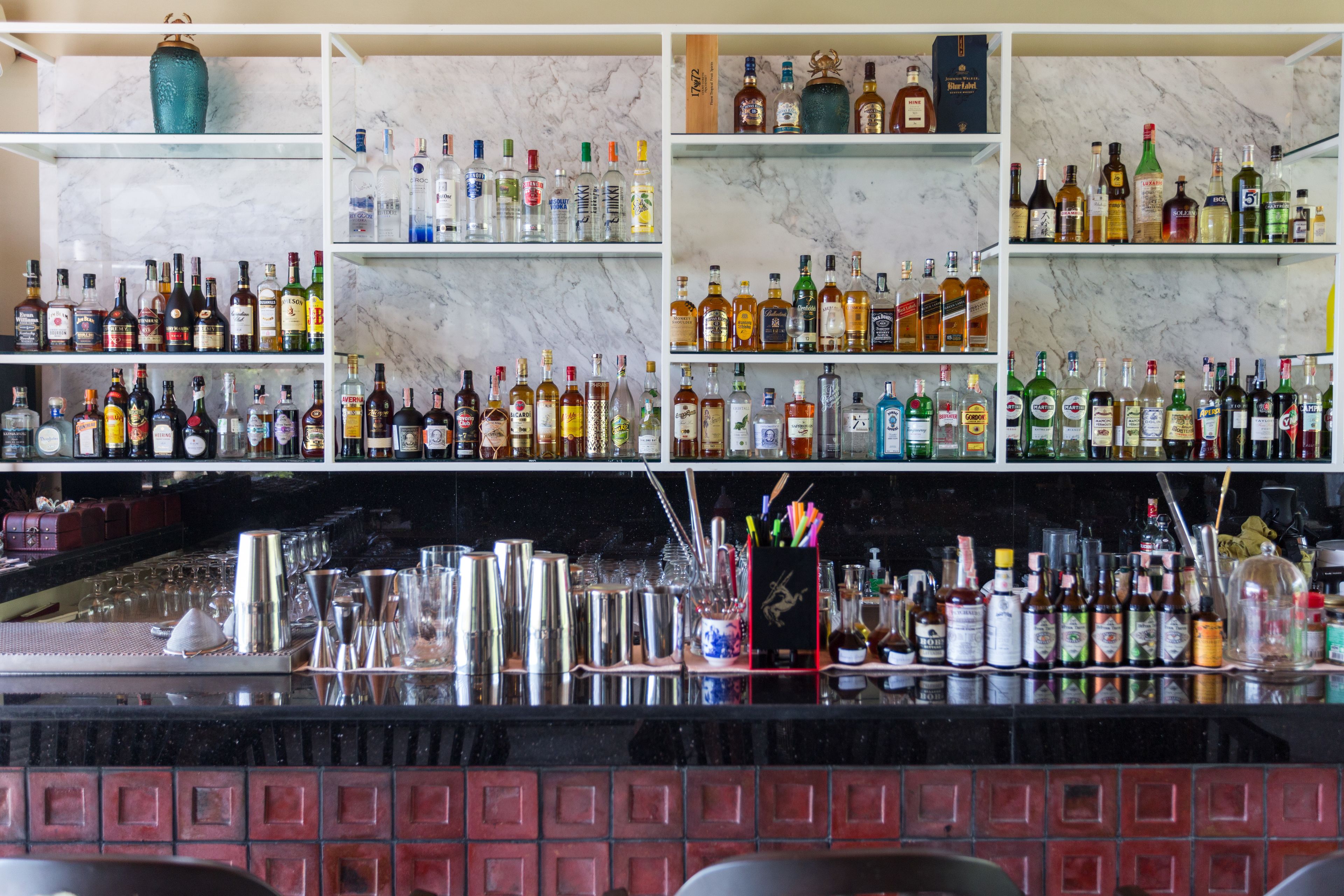 Una barra con estantes repletos de botellas de licores y utensilios de bar.