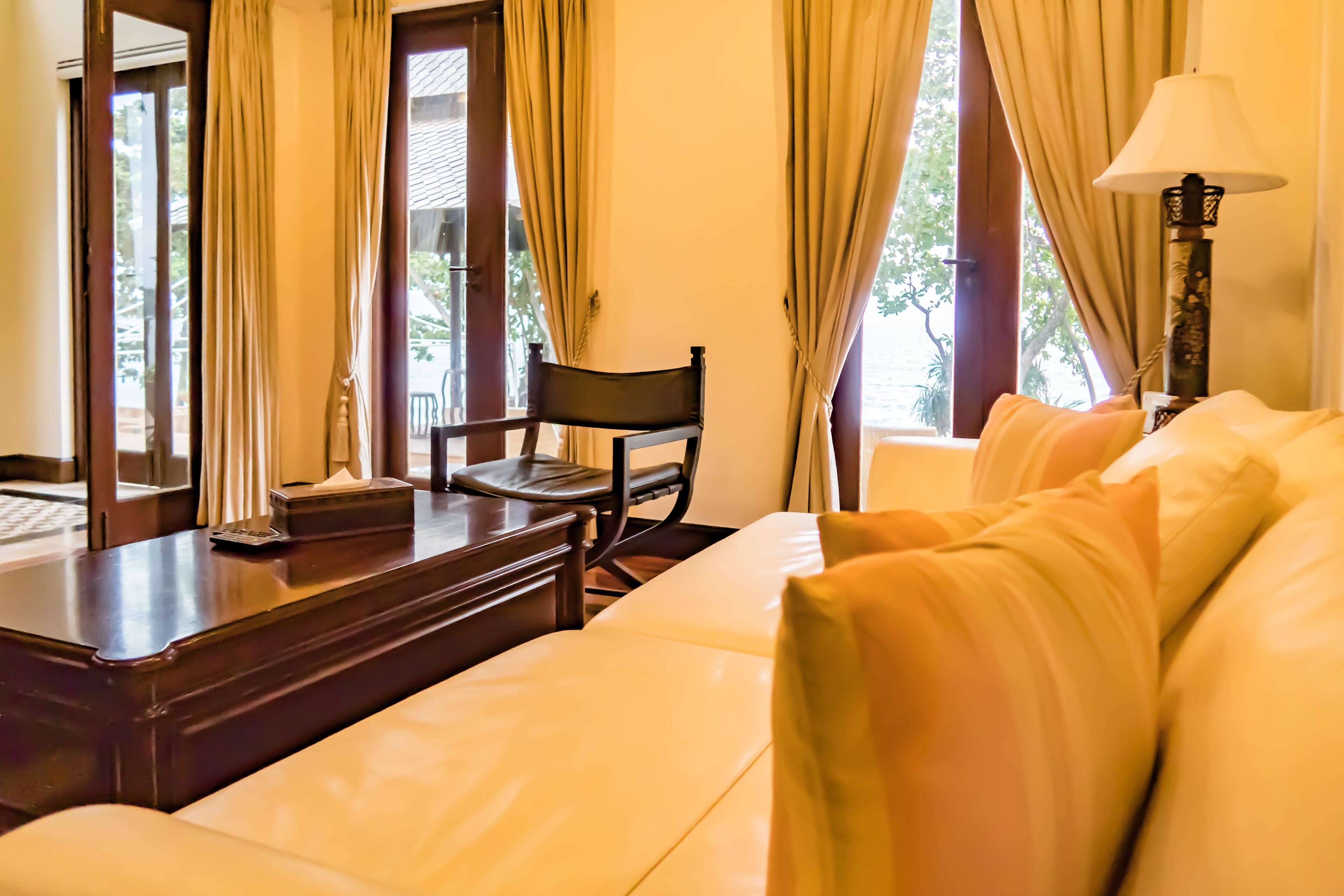 A hotel room with a sofa, a chair, a table, and a lamp.
