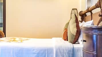 A neatly made bed with a white bedspread, a wooden headboard, and a bedside table with drawers.