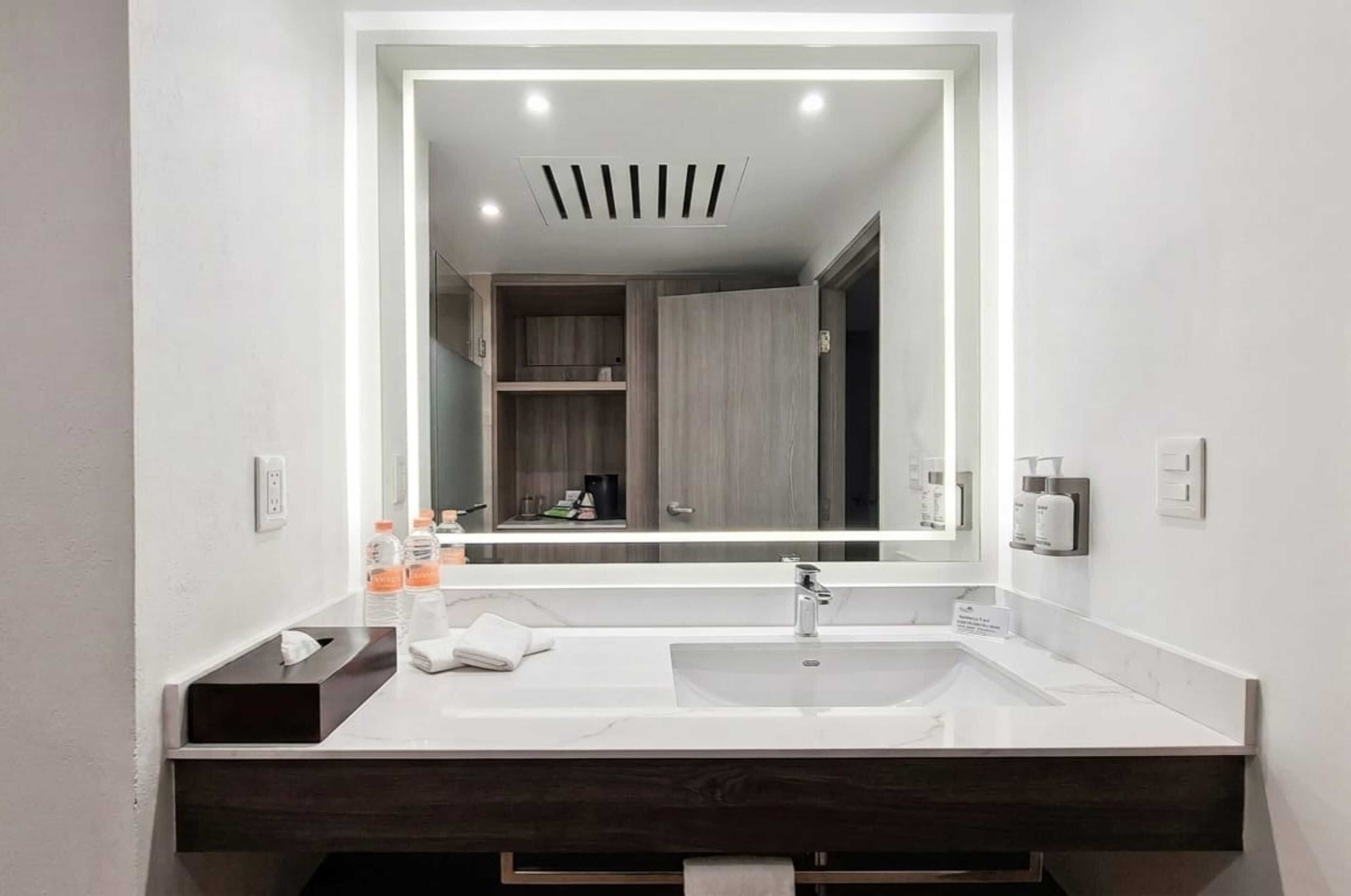 A modern bathroom with a large mirror, dual sinks, and a dark wood vanity.