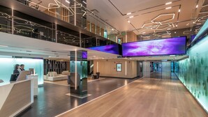 Un hall d’hôtel moderne doté d’un comptoir d’accueil, d’un espace salon et de grands écrans numériques.