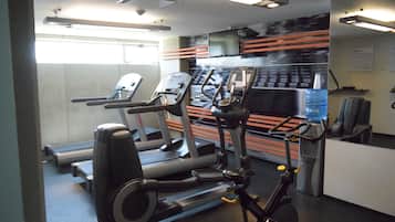 Un gimnasio con cintas de correr, máquinas elípticas y un dispensador de agua.