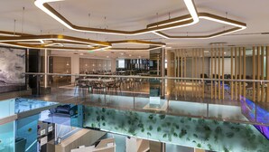 A modern interior with a glass railing, a car display, and a dining area with tables and chairs. - Holiday Inn Express Toluca Galerias Metepec by IHG (Toluca)