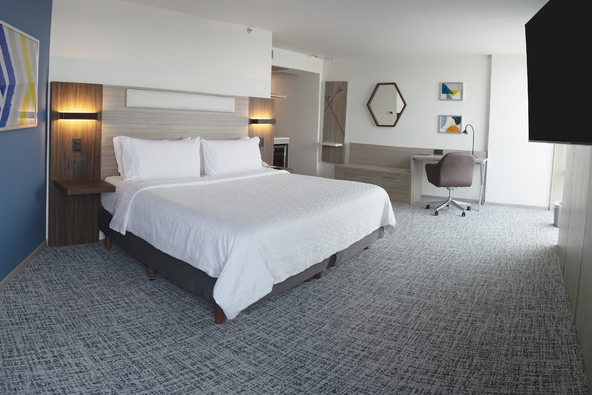 Una habitación de hotel con una cama grande, un escritorio, una silla y un televisor.