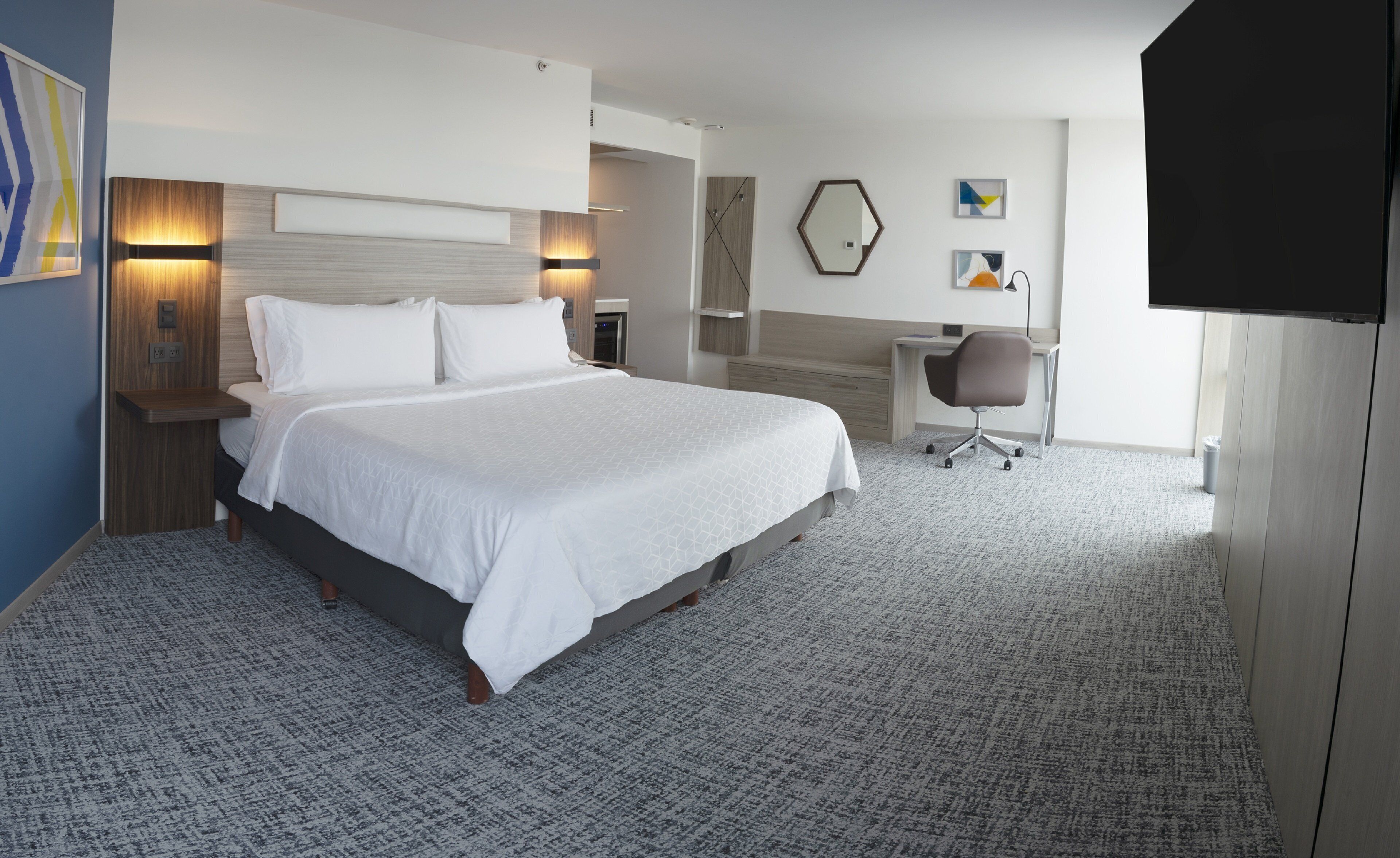 Una habitación de hotel con una cama grande, un escritorio, una silla y un televisor.