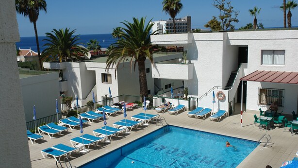 Zona de piscina con sillones de descanso, una piscina y vista al océano.