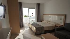 Una habitación de hotel con cama, dos mesitas de noche, un sofá, una pequeña mesa y vistas al exterior.