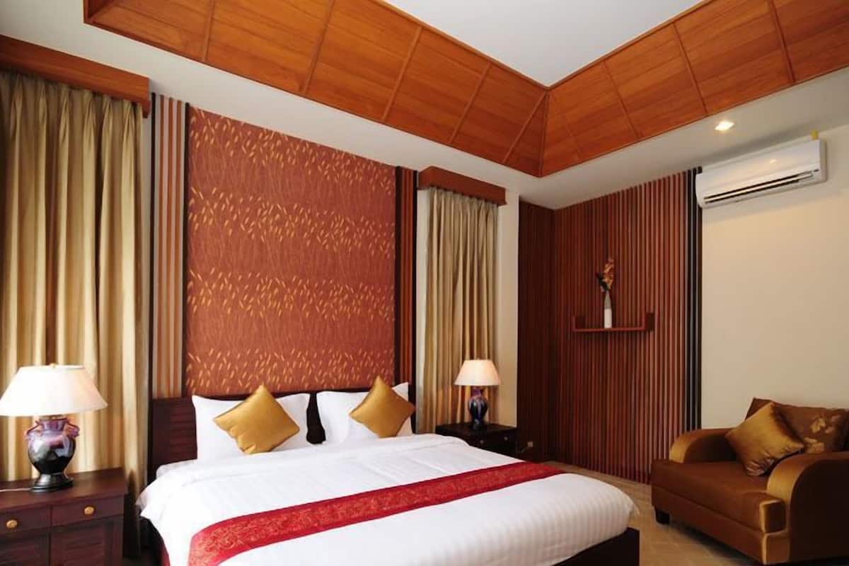 A hotel room with a large bed, two bedside tables with lamps, a sofa, and a decorative wall panel.