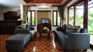 A living room with two sofas, a coffee table with fruit, and a TV. - Bhumlapa Garden Resort (Koh Samui)