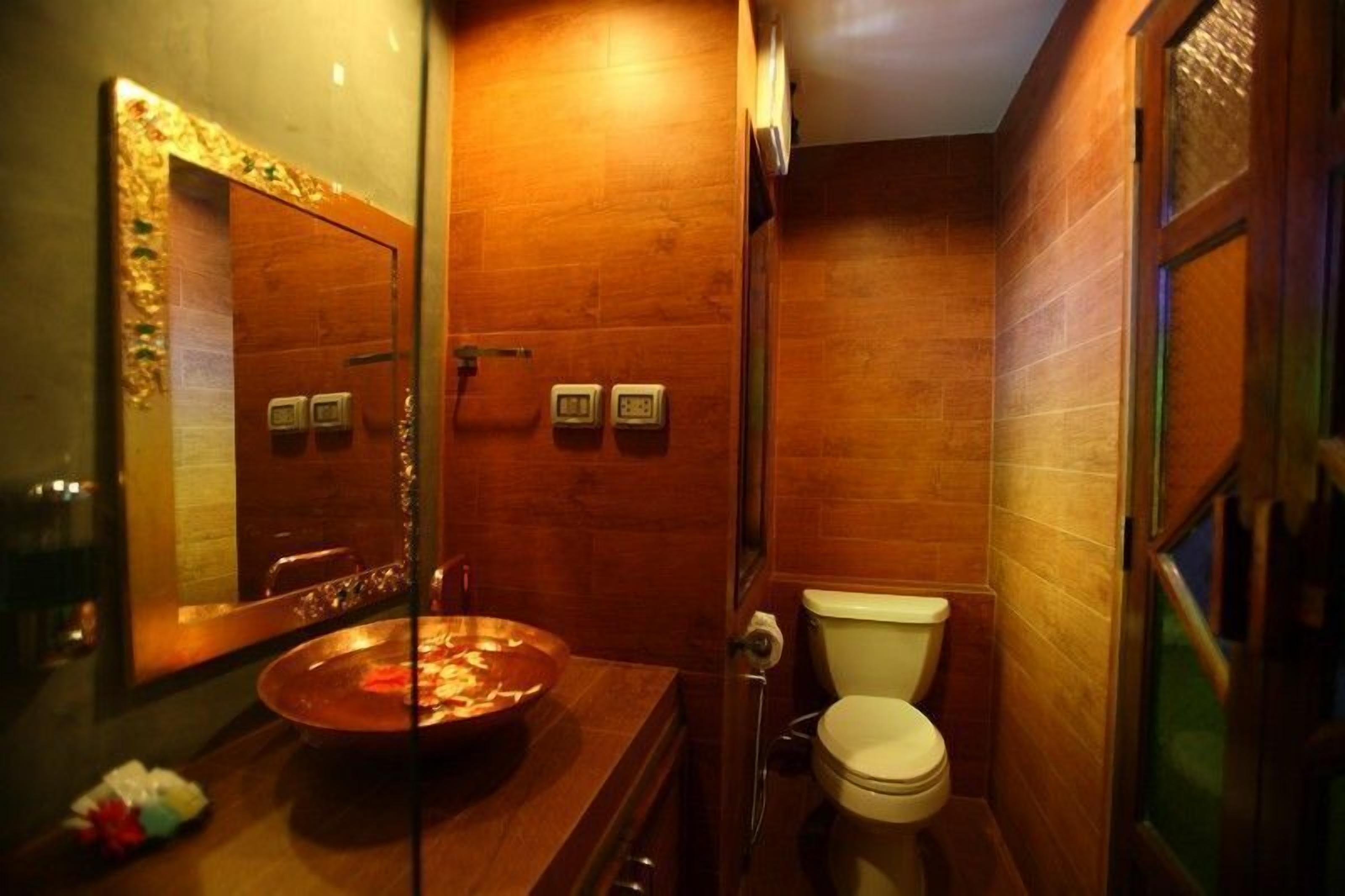 Un baño pequeño con tocador de madera, un lavabo redondo y un inodoro.