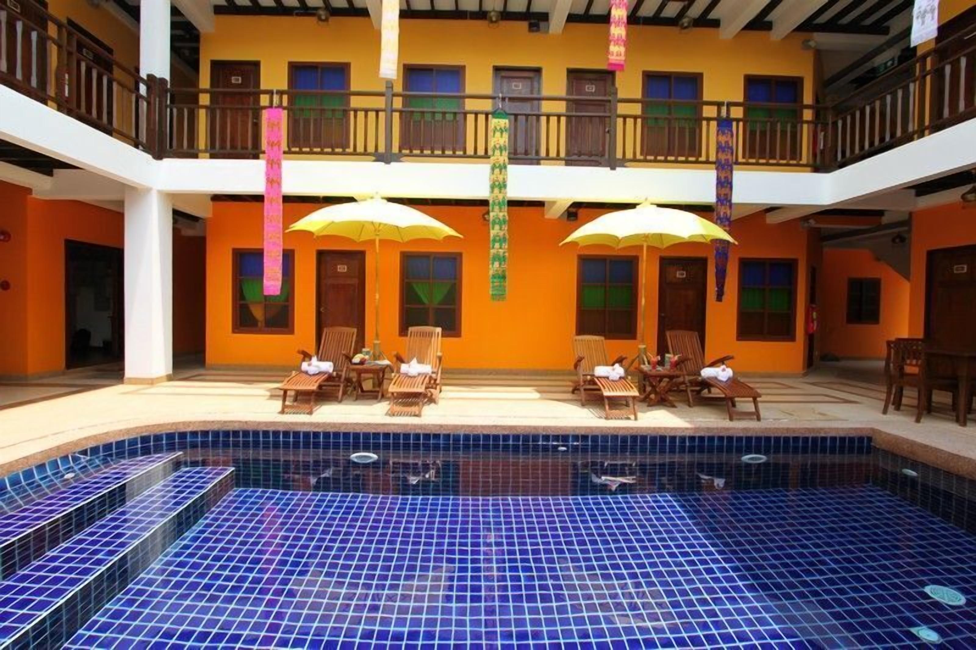 Un hotel con piscina, varios balcones y zonas de estar al aire libre.