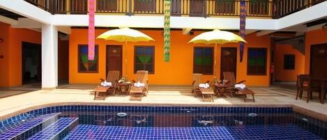 Un hotel con piscina, varios balcones y zonas de estar al aire libre.