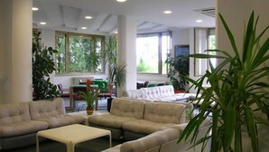 Uma sala de estar ampla com um conjunto de sofá bege, uma mesa de centro e várias plantas em vasos.